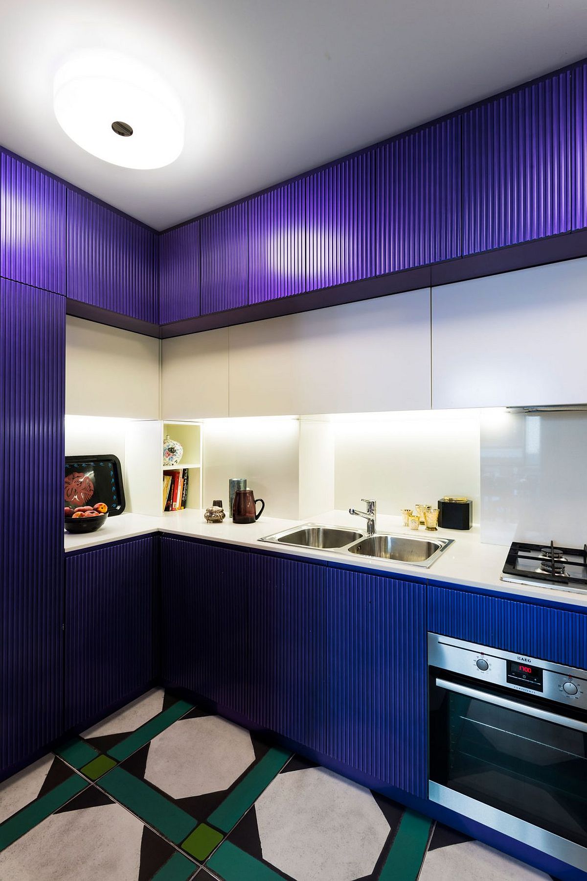 Lighting enlivens the small kitchen in dark blue and white