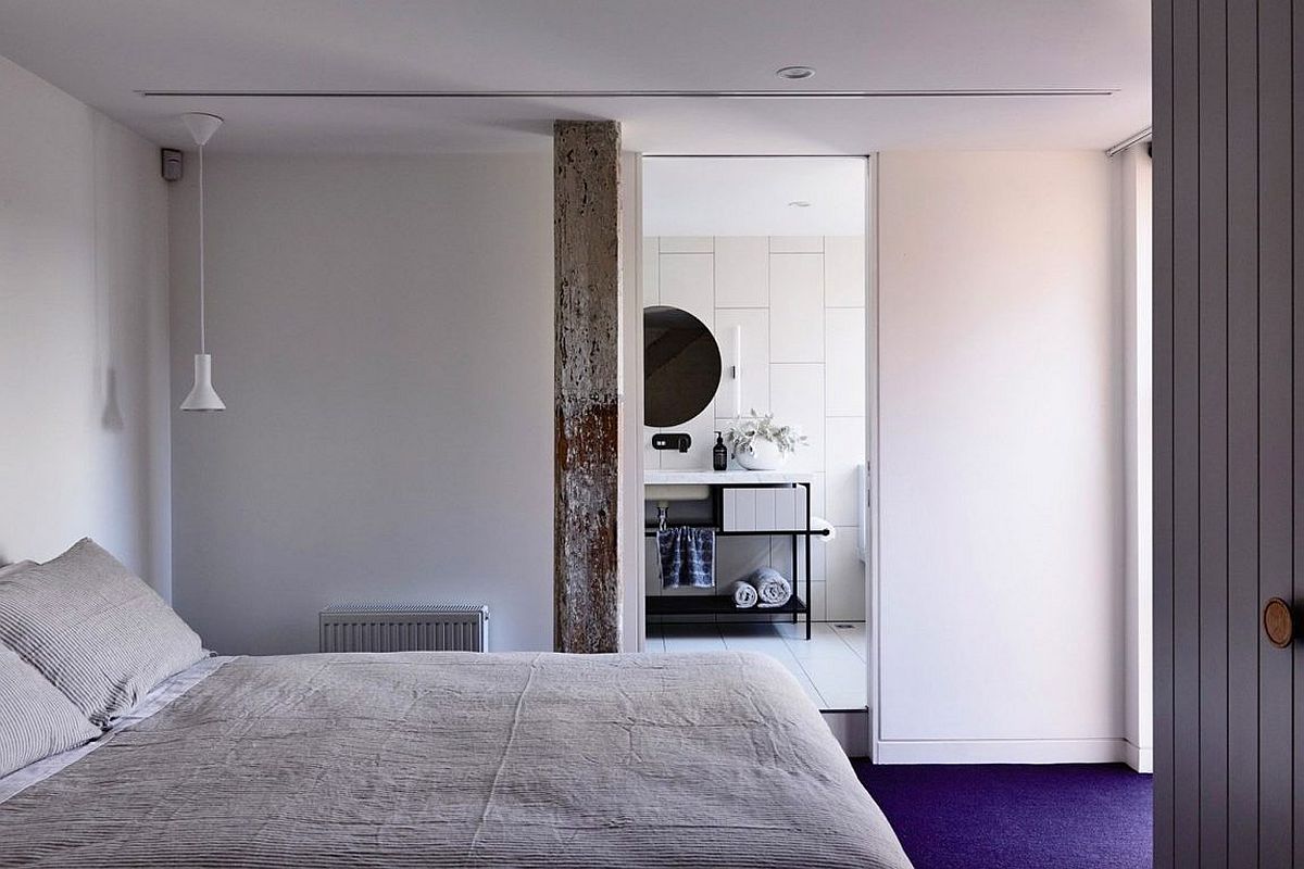 Bedroom and bathroom of the industrial loft delineated by sliding door