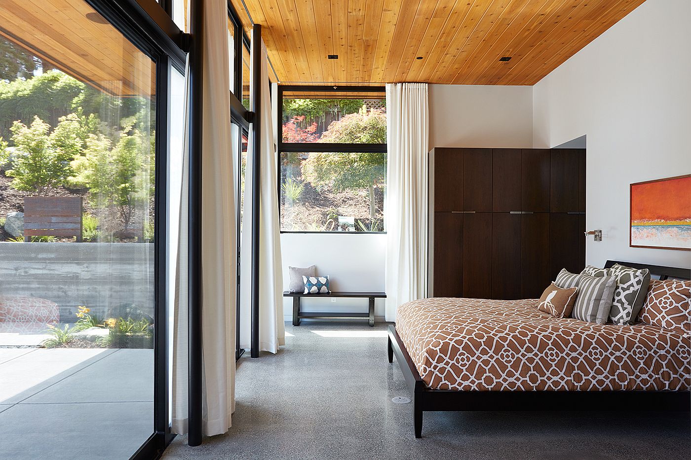 Contemporary light-filled bedroom with sliding glass doors and white drapes