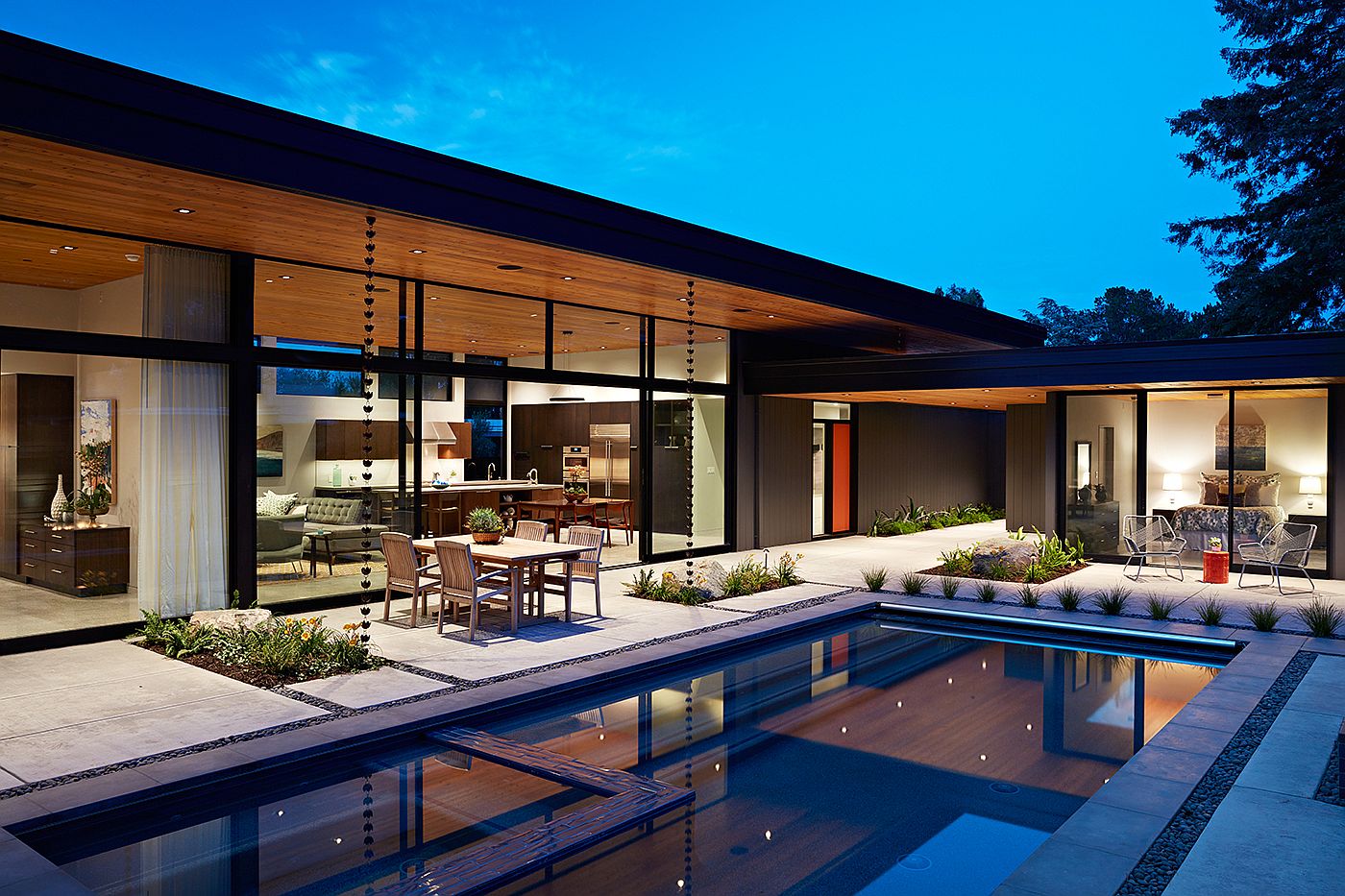 Large glass walls connect the interior with the rear yard and the pool