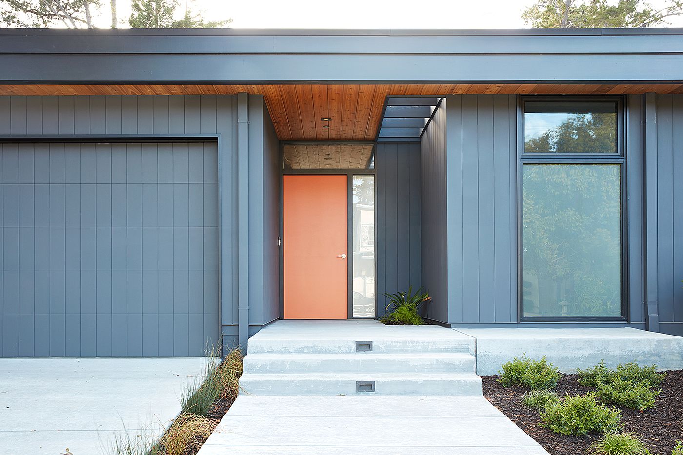 Orange door and gray exterior give the home a classic Eichler-inspired look