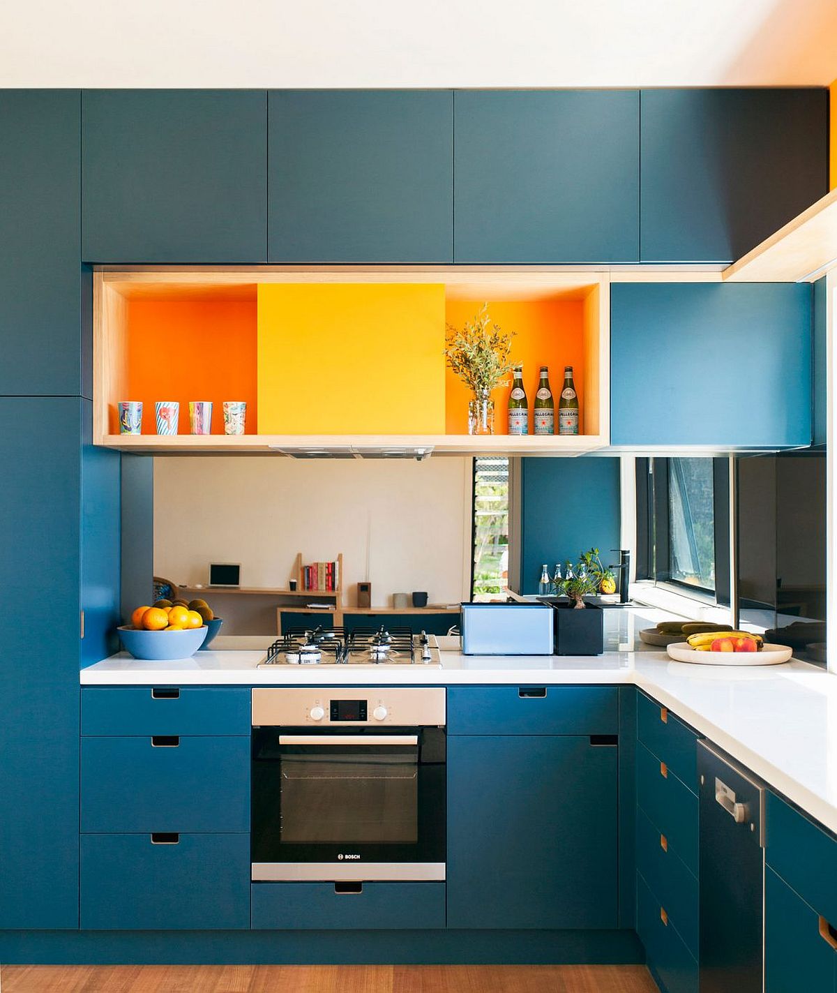 Bright blue cabinets and orange bring energy to the modern kitchen