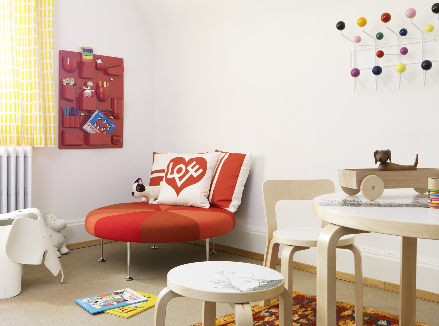 Colour Wheel Ottoman designed by Alexander Girard in 1967 (pictured in a Hopsak red mix). 'Love' graphic print pillow by Alexander Girard. Uten.Silo II (in classic red) designed by Dorothee Becker in 1969.