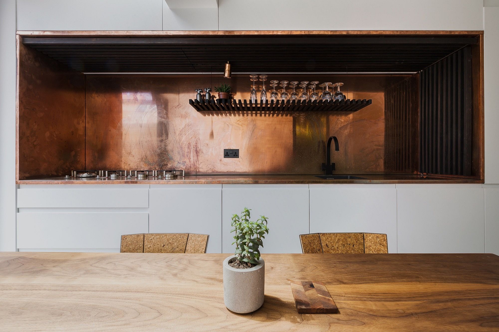 Exquisite kitchen workspace and backsplash in copper along with charred larch slats