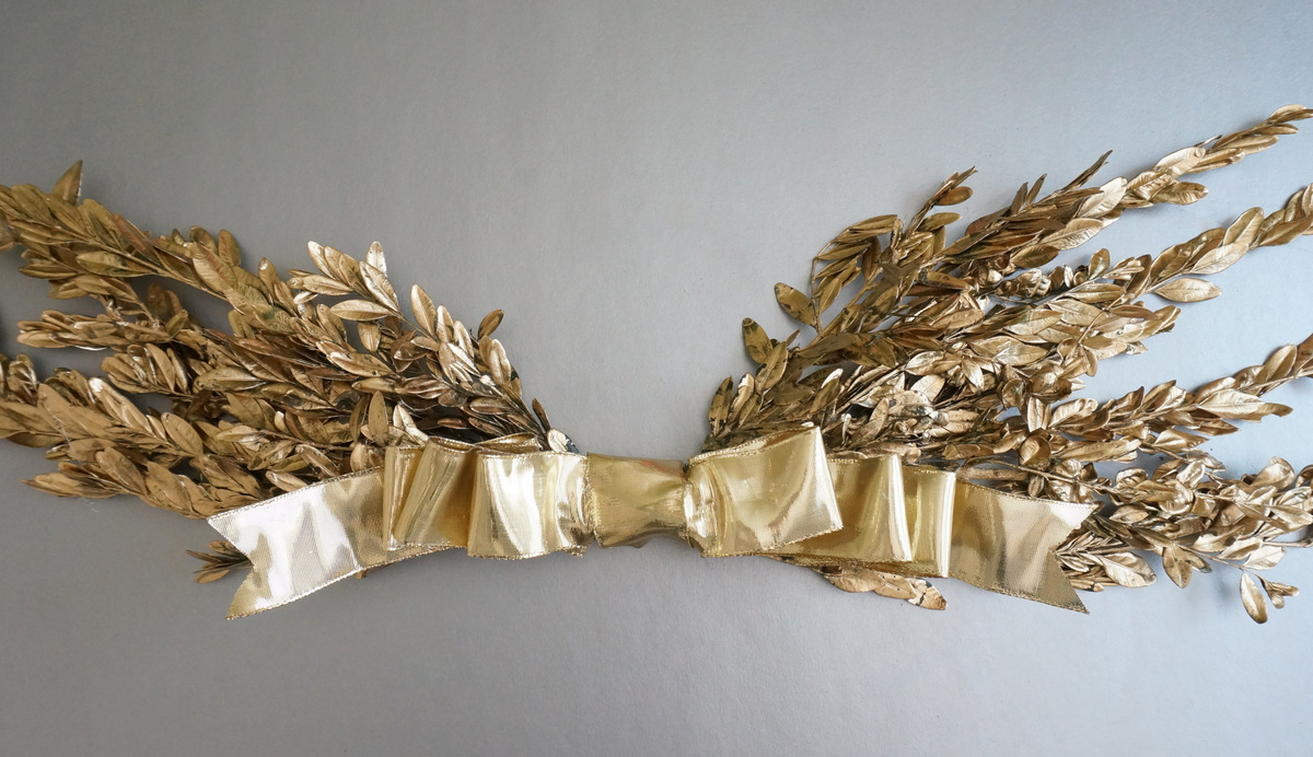 Gold holiday wall hanging with a bow