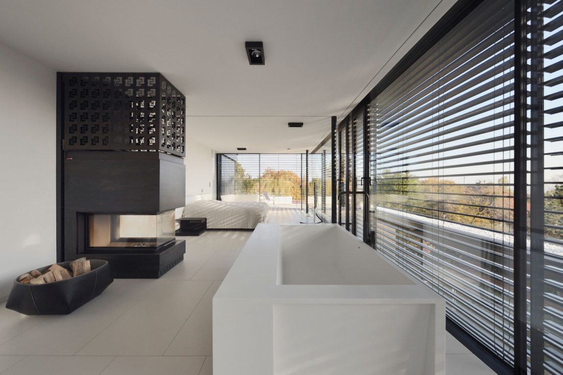 Bedroom in white with a black fireplace and ample sunlight