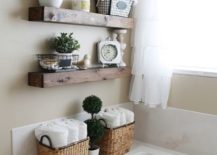 Chic bathroom with floating shelves that hold a clock, towels, and a metal wire basket.