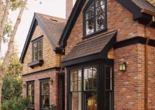 Red brick house with black awnings and trim.