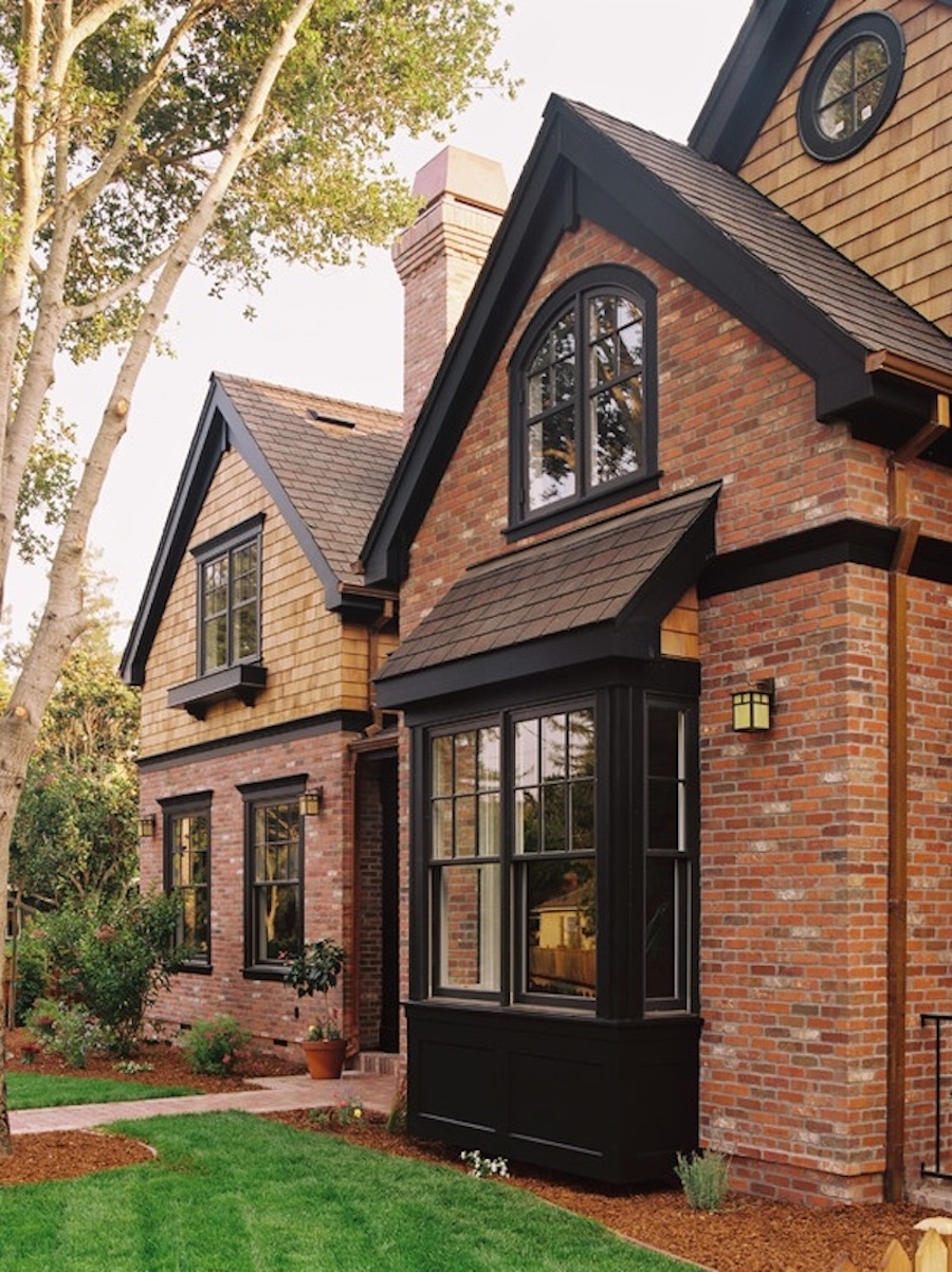 Red brick house with black awnings and trim.