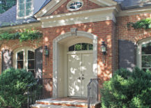 Red brick house with matching driveway, featuring a large white front door.