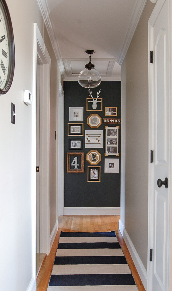 Hallway gallery with multiple framed pictures on a dark wall.