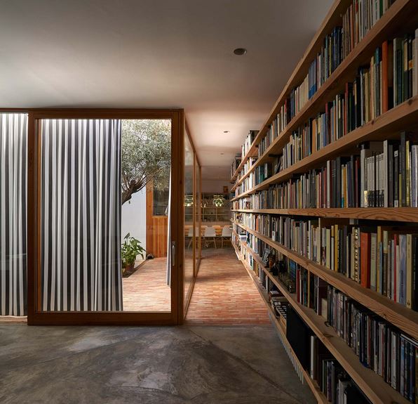 Book shelves are neatly arranged, and the sliding door is partially open, revealing a glimpse of the outside world.