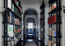 A hallway with bookshelves showcasing a variety of books, complemented by a patterned black and white rug.