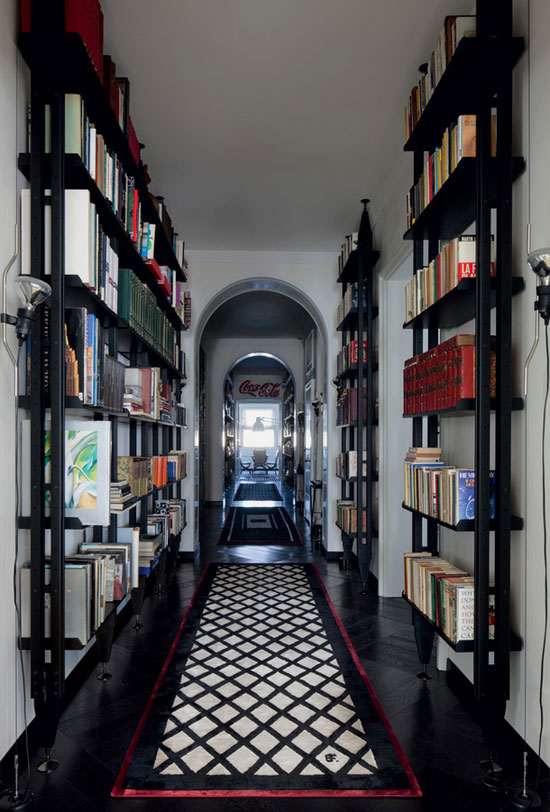 A hallway with bookshelves showcasing a variety of books, complemented by a patterned black and white rug.