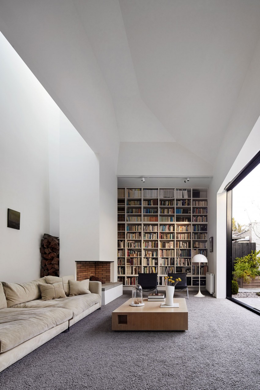 A modern living room showcases a spacious bookcase filled with books and a long couch.