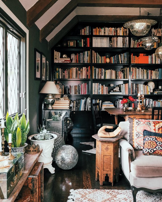A cozy living room with wooden bookshelves filled with books and a comfortable couch placed in the center.