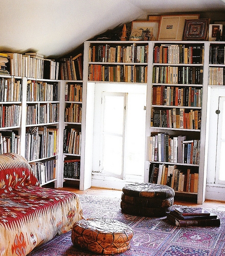A living space adorned with a comfy couch, bookshelves above the doorway, and a stylish rug.