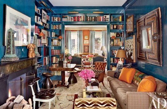A busy living room with vibrant blue walls and lined with elegant bookshelves.