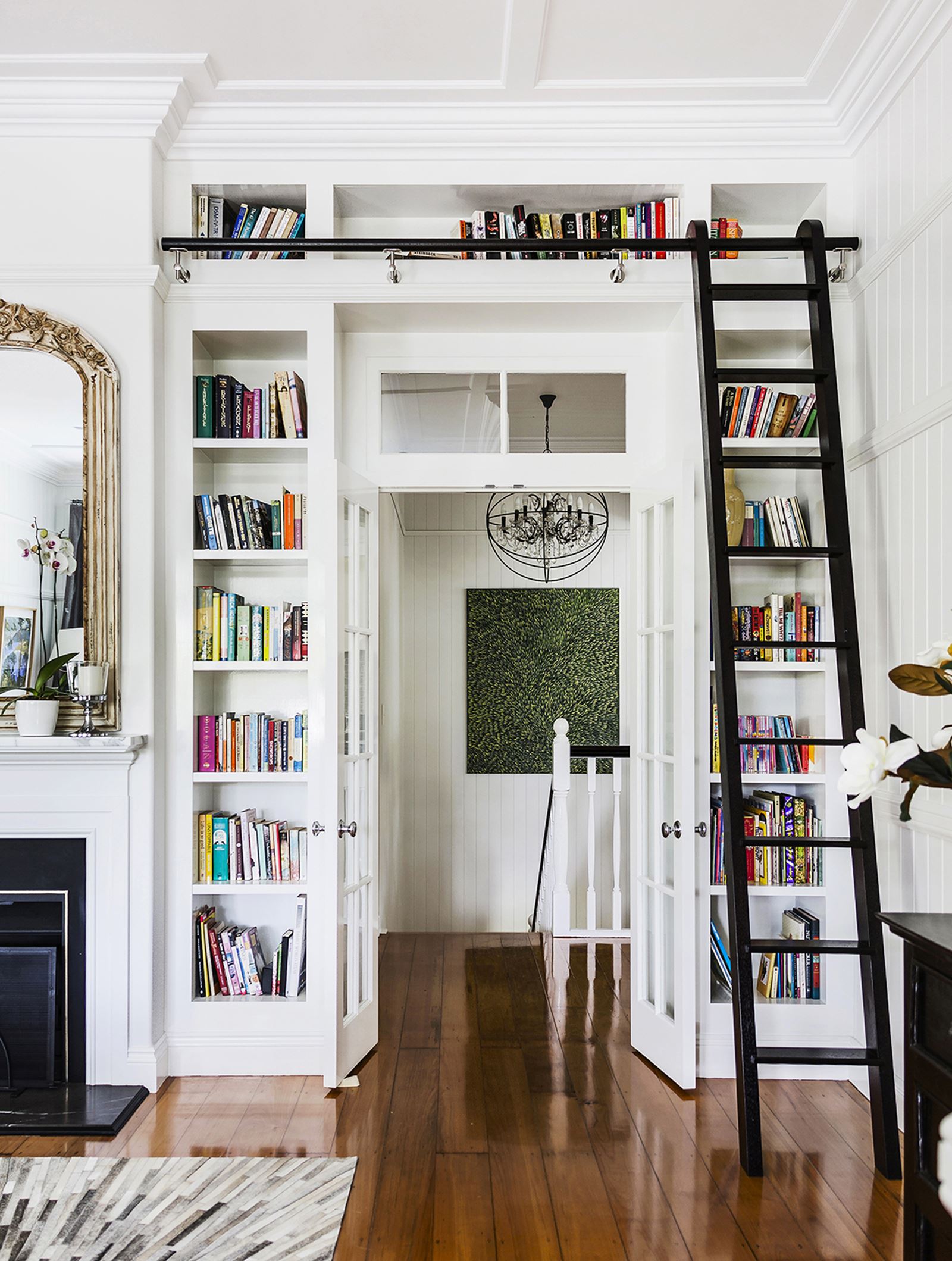 A white-themed room with a ladder to the above-door bookcase.