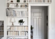 A white room adorned with bookshelves mounted above the doorway.