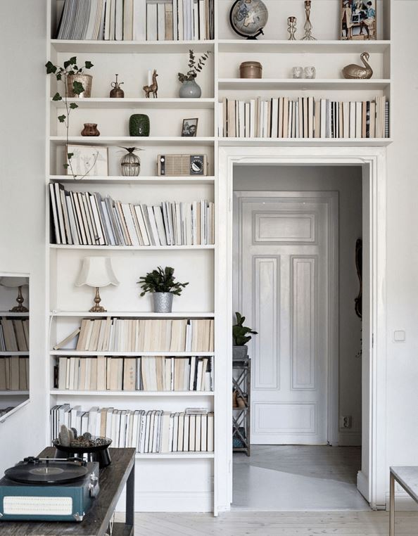 A white room adorned with bookshelves mounted above the doorway.