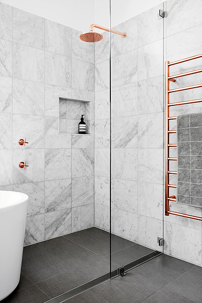 A contemporary bathroom featuring a pristine tub and a shower with copper accents.