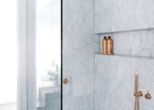 A luxurious bathroom featuring elegant marble walls and a sleek shower finished with touches of copper.