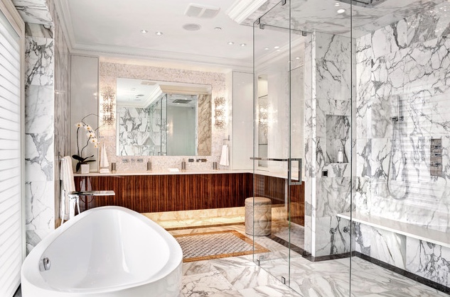 A luxurious bathroom featuring exquisite marble flooring and a spacious tub flanked by a wooden vanity.