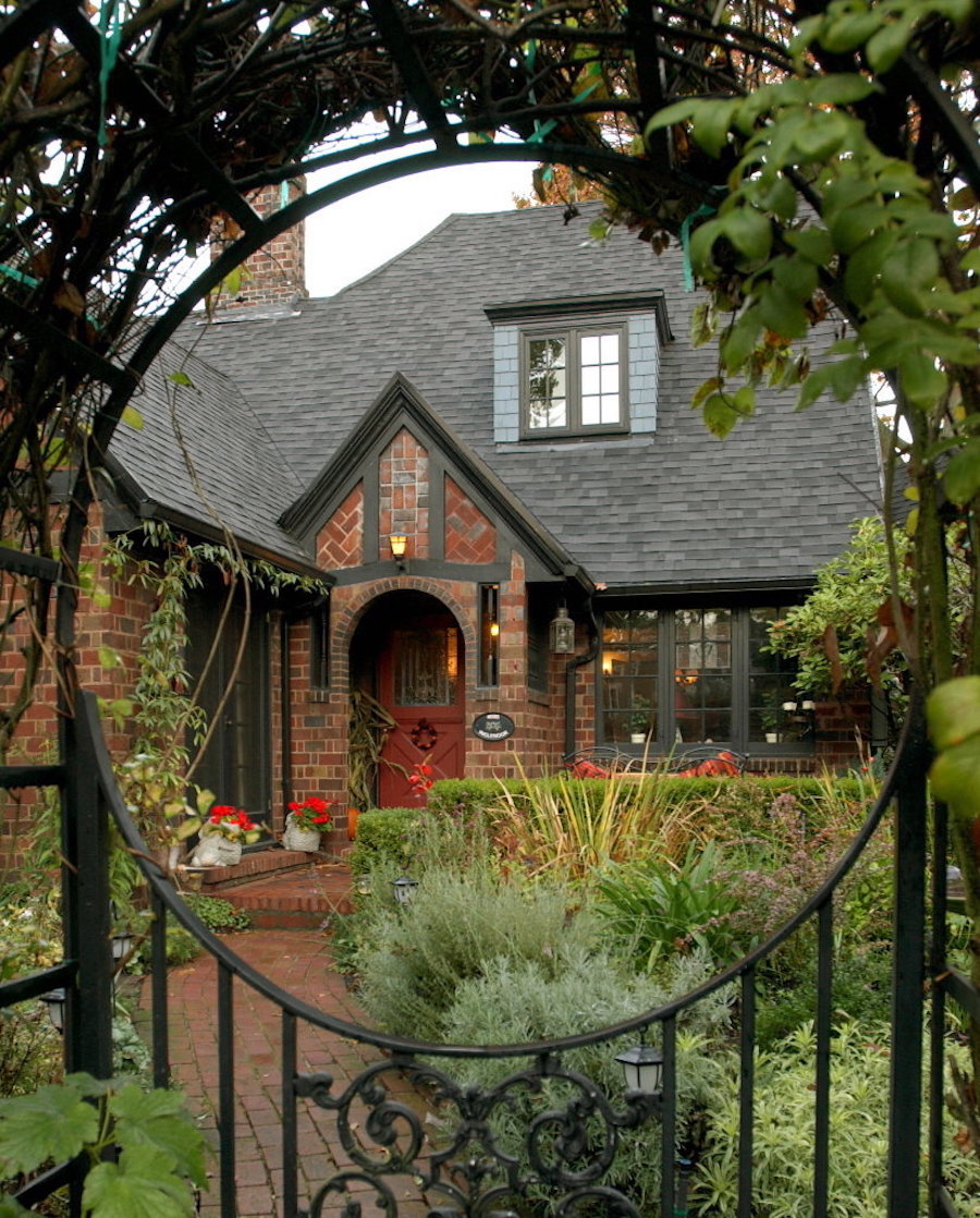 Red brick house with black fence that has a circular design.