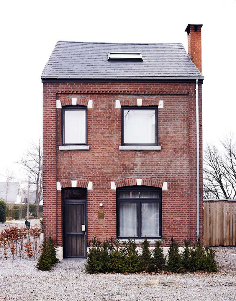 Red brick house with black window trim and chimney.