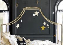 Bed with a gold frame that extends over, hanging golden stars.