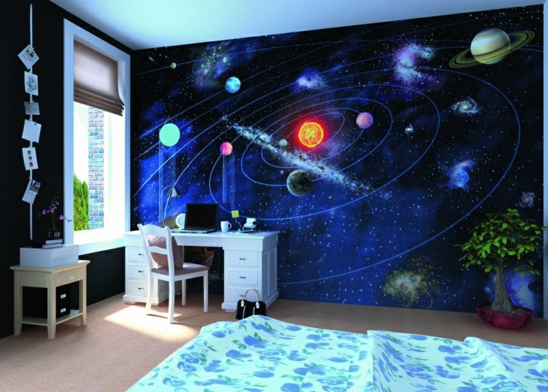Espaço de quarto de criança com decoração de parede universo e mesa branca.