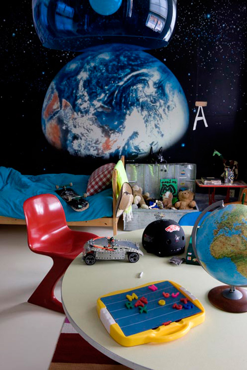 Espaço de quarto infantil com acessórios educativos ladeado por uma pintura da Terra.