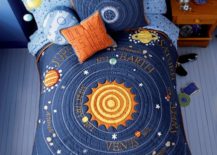 Space children's room with a bed that has covers that feature the sun in the center with planet names around it.