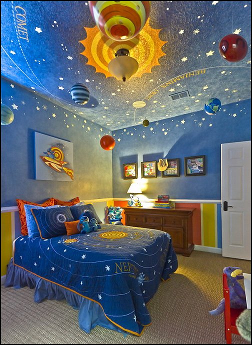 O quarto infantil espacial é pintado de azul e tem planetas pendurados no teto.