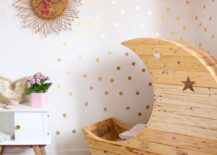 Space-themed nursery with a crescent moon cot flanked by wall decorations.