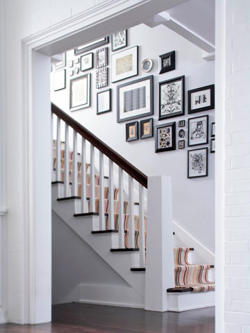 A white-themed stairway gallery with black framed pictures.