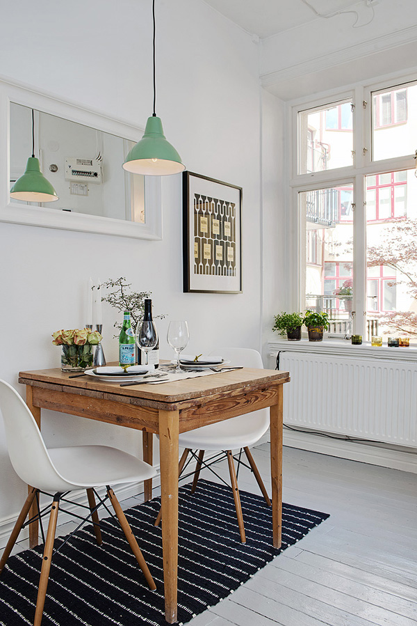 A bright white small dining room with a wooden table and two white chairs.