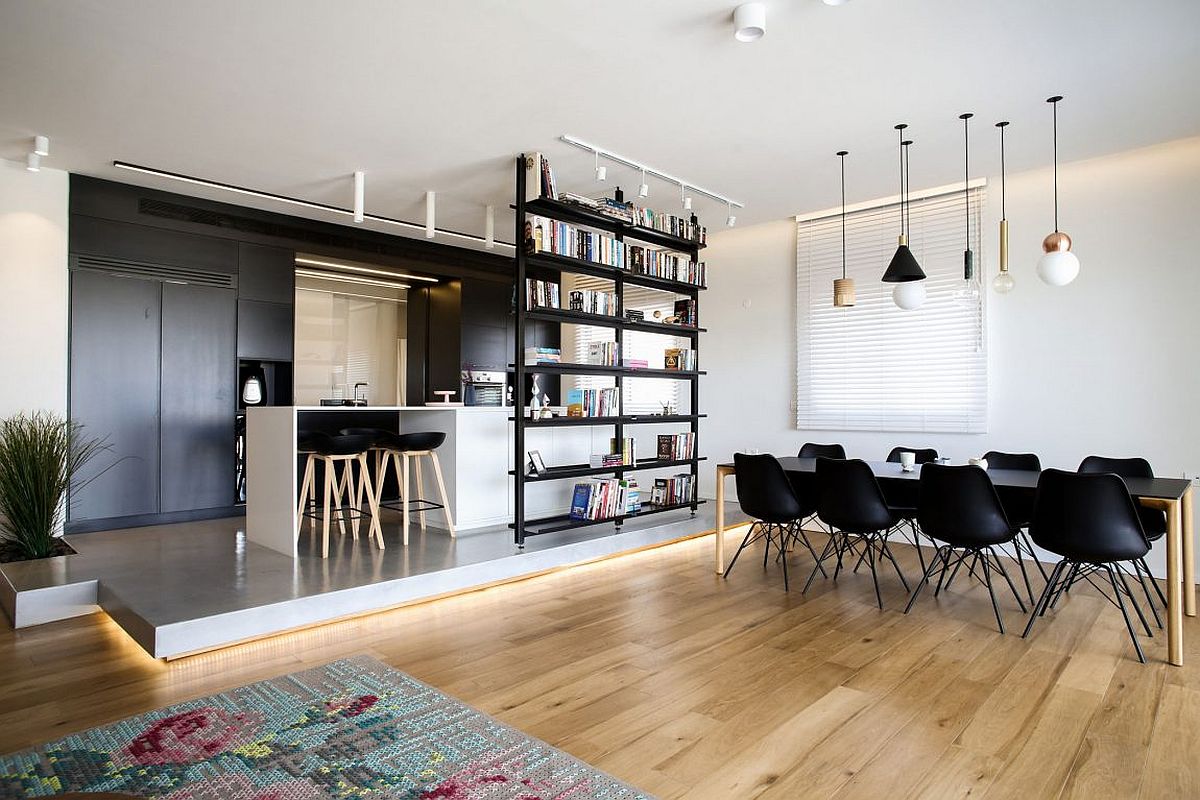 Two-sided bookcase acts as a divider of space between the kitchen and serving zone