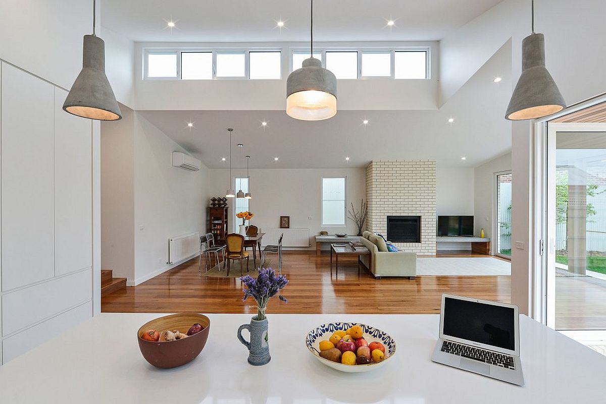 View of the living room and dining space from the contemporary kitchen in white