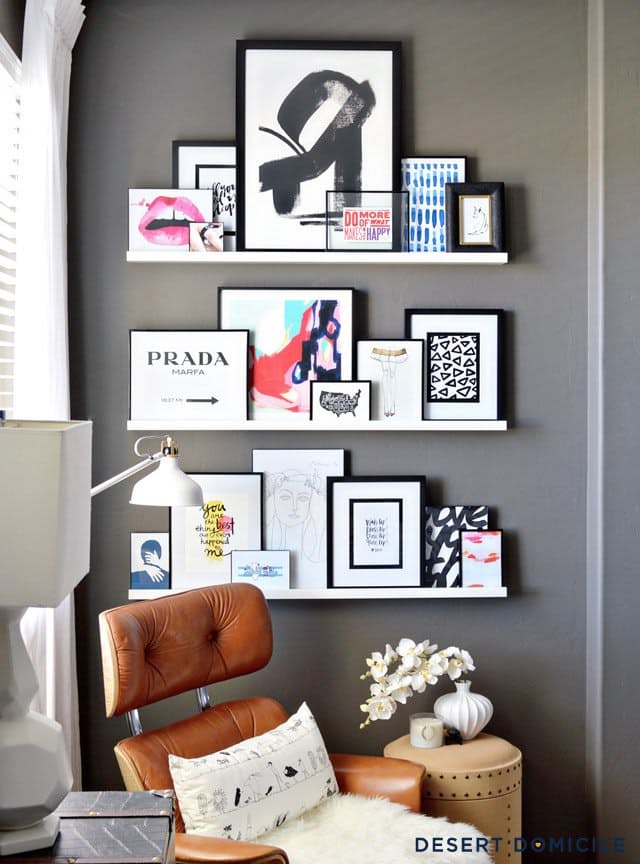A leather chair flanked by three white floating shelves displaying art pieces.