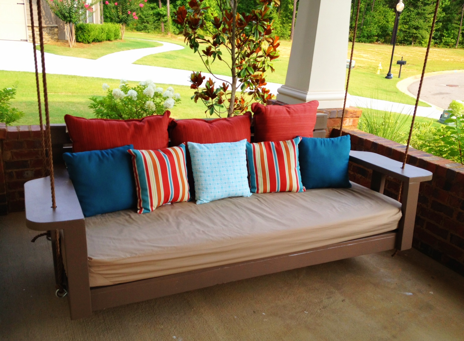 A chestnut brown swing with multicolored cushions