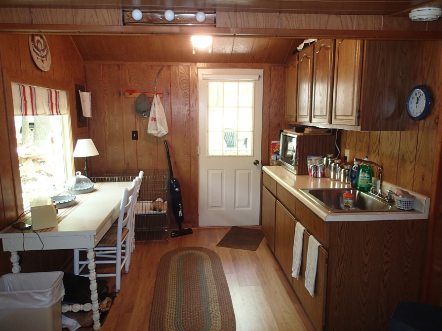 Cozy interior of a tiny home that's finished with wood all over and has a white desk and chair by window.