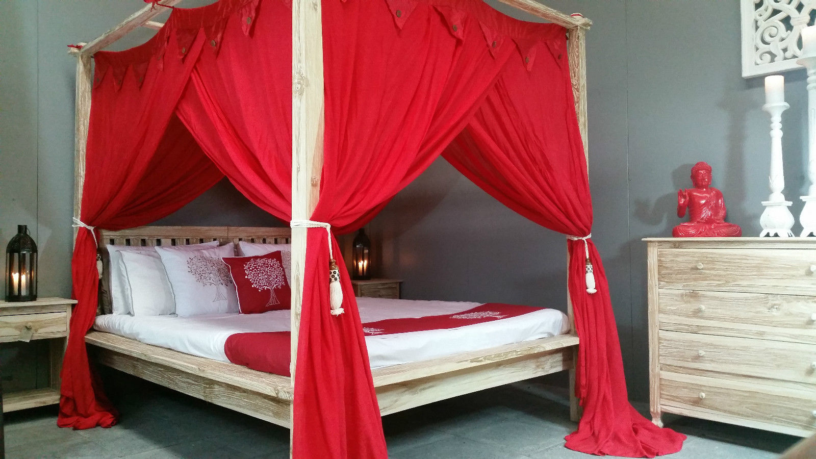 Boho bedroom with bright red canopy and wooden four poster bed