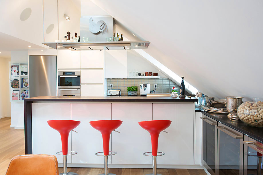 Bold red stools as an unconventional decor in an attic kitchen