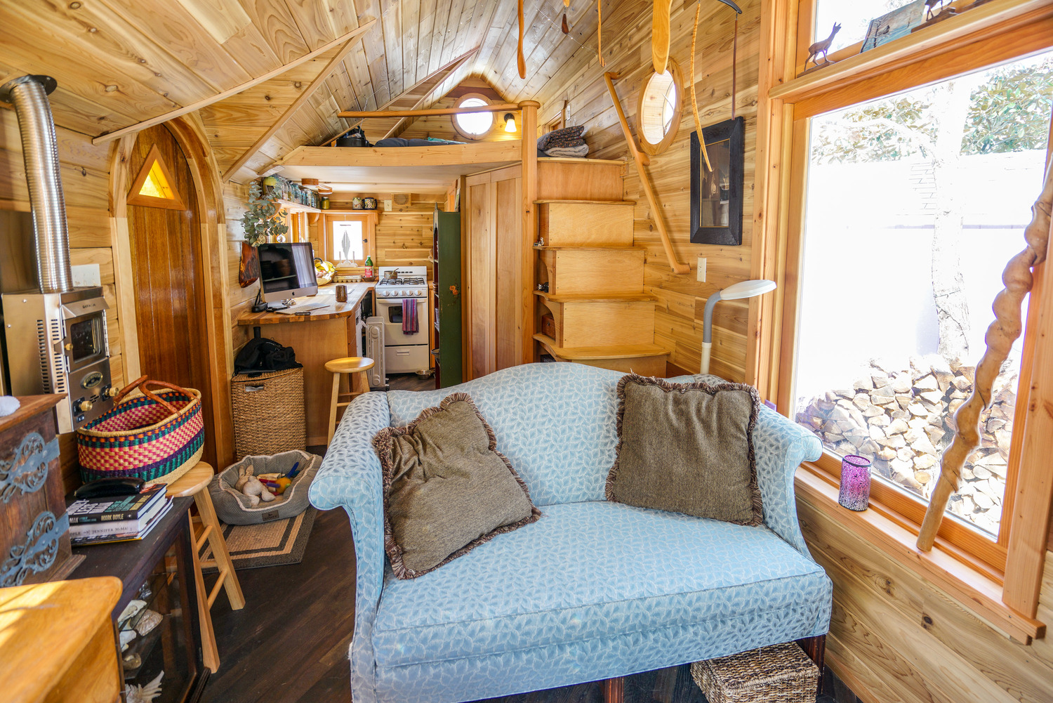 Tiny home interior entirely finished with wood, featuring a blue couch as the focal point.
