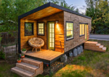 Rustic tiny home exterior finished in wood and has a cozy circular outdoor seat.