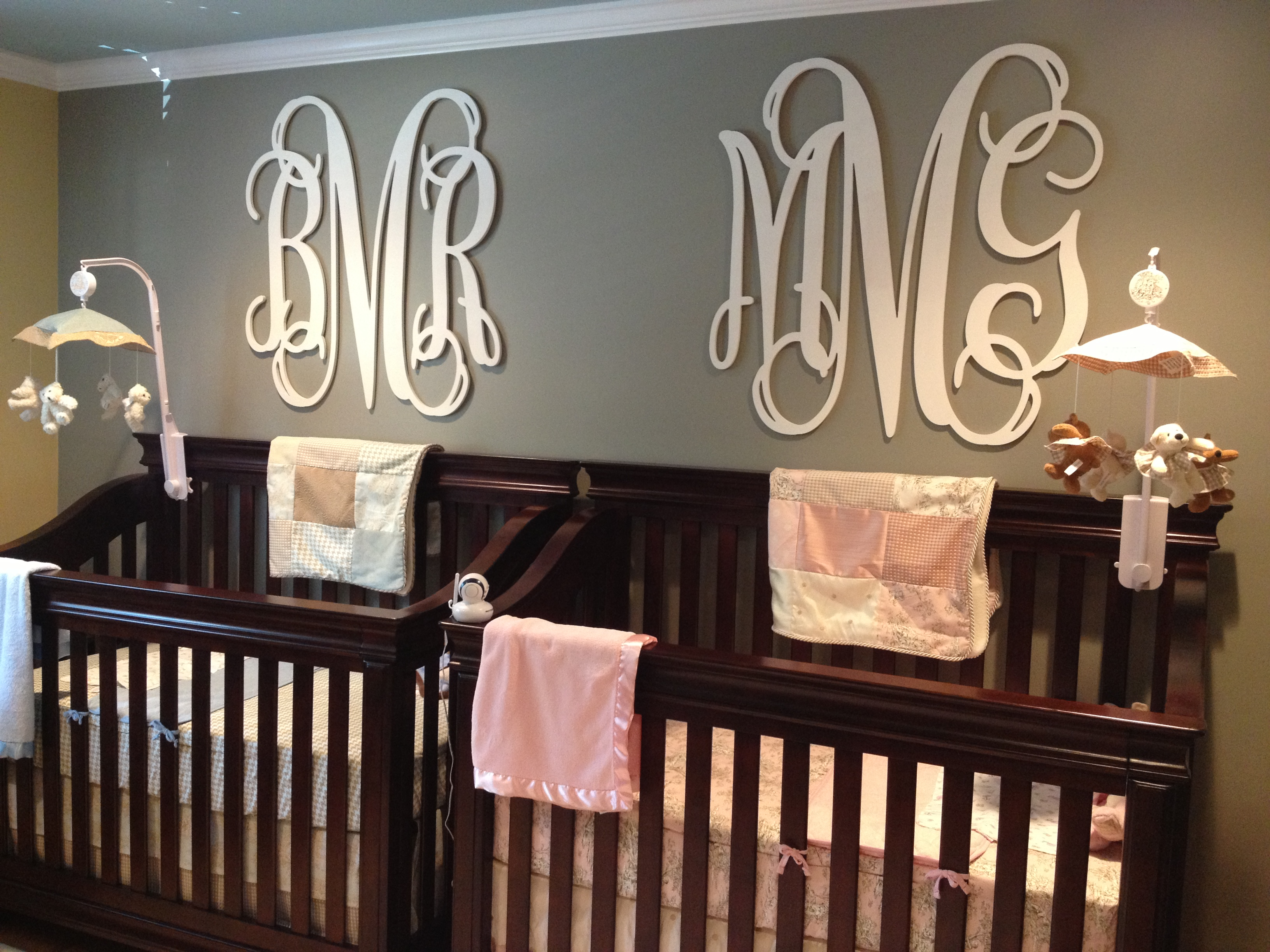 Identical cribs with big monograms above them