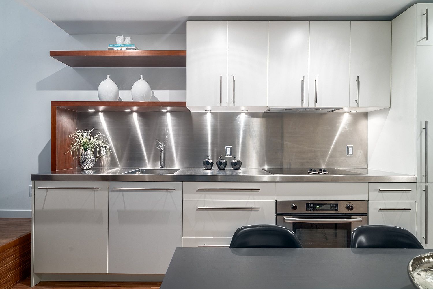 Kitchen with stainless steel backsplash and white cabinets