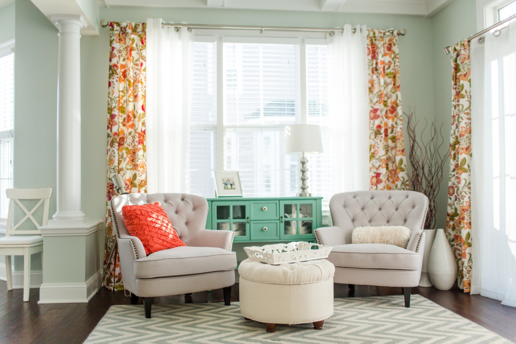 Mint walls with cream armchairs and orange curtains